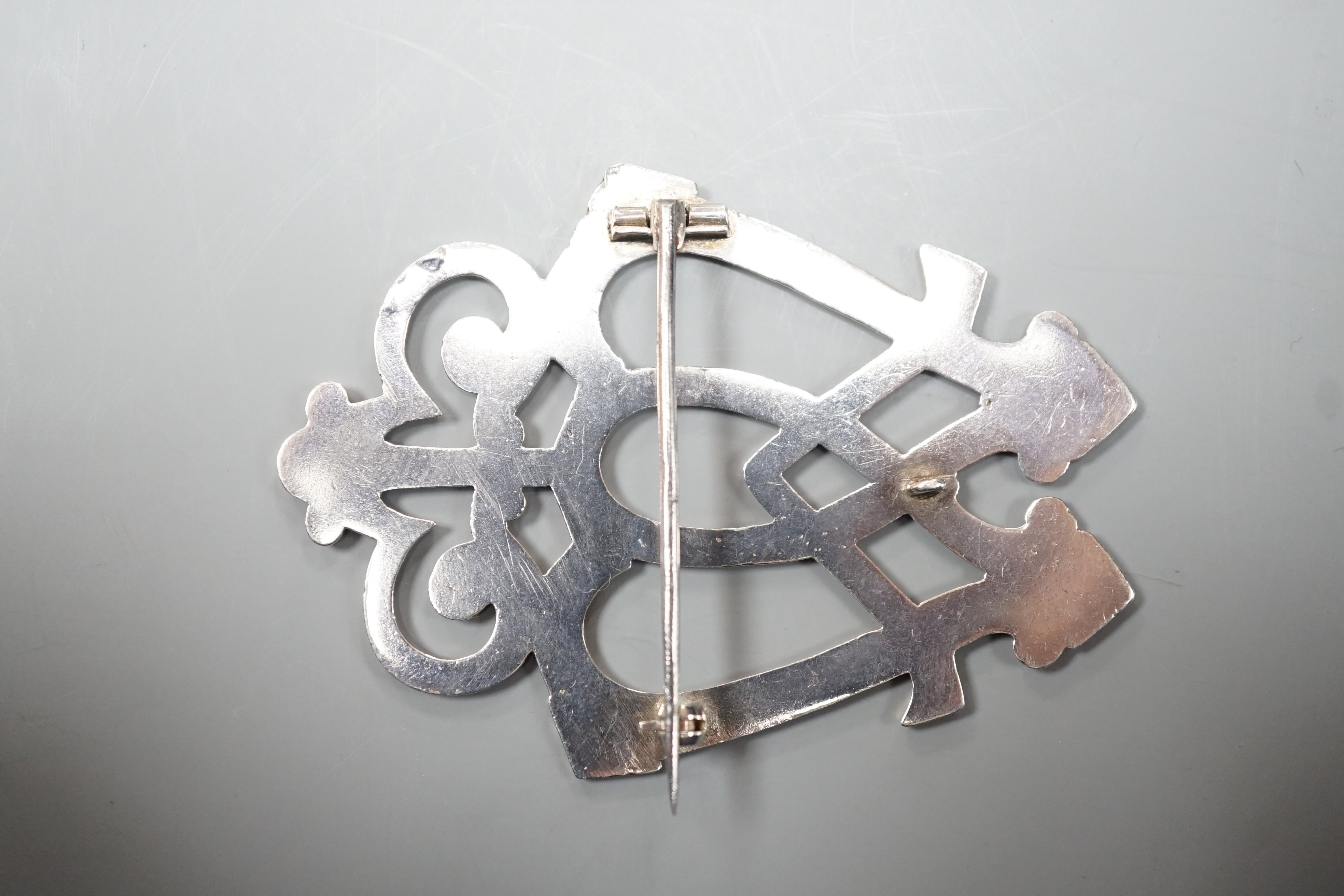 A white metal entwined twin heart brooch, with scrolling terminal, unmarked, 70mm.